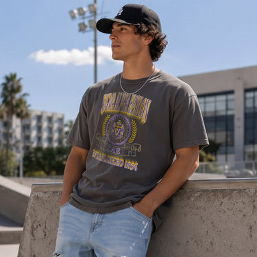 College-aged male wearing the fraternity Collegiate Crest Graphic Tee in charcoal grey, featuring vintage Sigma Alpha Epsilon crest artwork on campus.