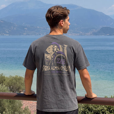 Man wearing a grey comfort colors tee with premium ancient Greece Odyssey design