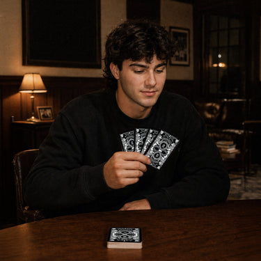 Fraternity brother holding custom Heritage Playing Cards during a poker game in a chapter house lounge.