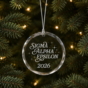 Limited Edition glass Christmas ornament with engraved design hanging on a decorated holiday tree
